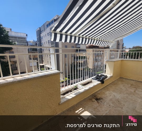 מרפסת עם מעקה מתכת לבן וסוכך פסים שחור-לבן